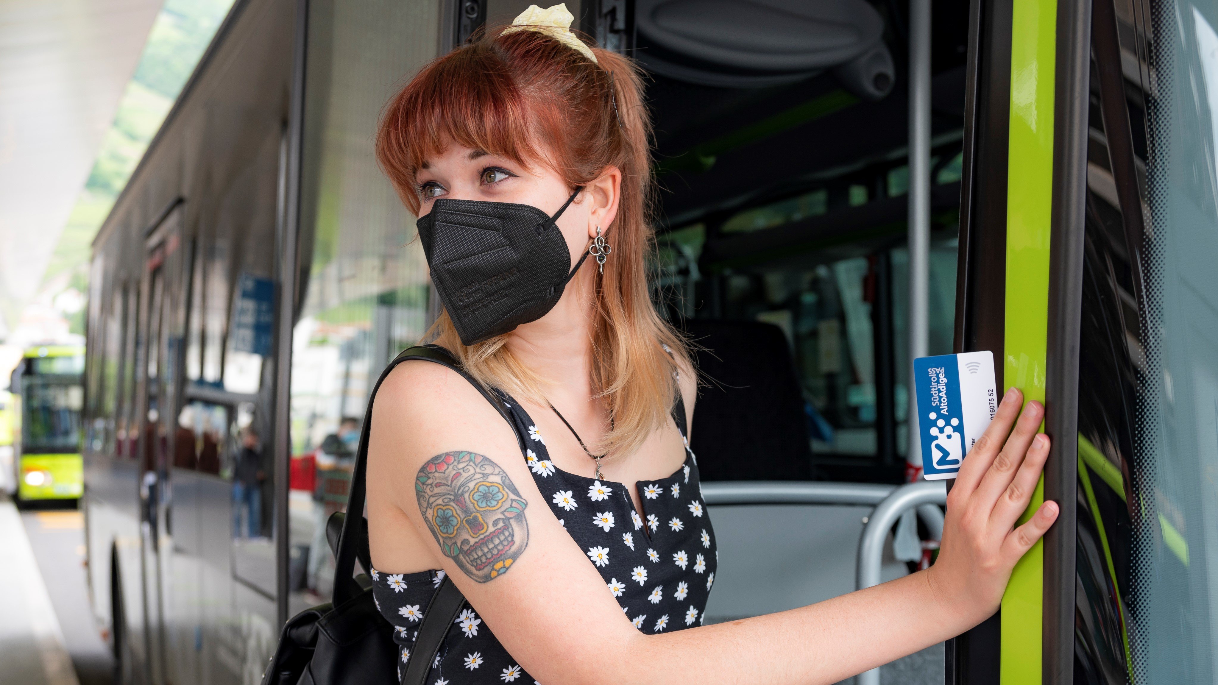 A girl wearing an FFP2 mask gets on the bus